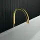 Freistehender Wanneneinlauf in Goldoptik vor schwarzer Wand, hergestellt von Ideal Standard. Die Form ist geschwungen und minimalistisch gestaltet.